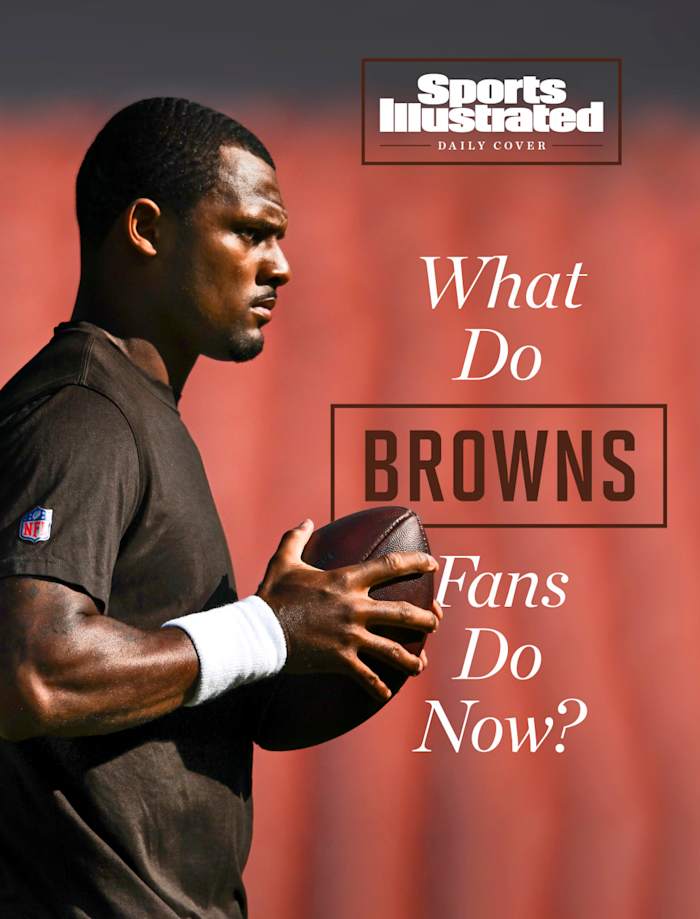 Deshaun Watson, in t-shirt, holds a football as he walks across the field at an empty stadium